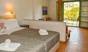 Hotellrom med to senger, en belyst veggmontert nattbord og en åpen dør til en balkong. (AI-generert tekst)