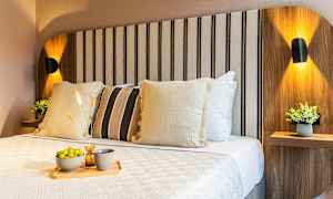 En opplyst seng med dekorative puter og en brett med potetgull og drikke. (AI-generert tekst)