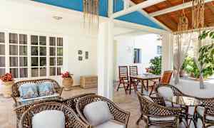 En luftig veranda med sittemøbler av rotting og en dekorativ takkonstruksjon. (AI-generert tekst)