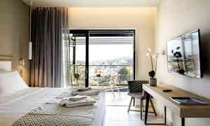 Hotellrom med seng, TV, skrivebord og balkong med utsikt. (AI-generert tekst)