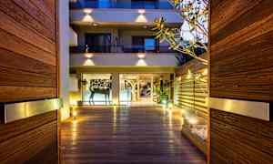 Inngang med trepanel og belysning som leder til en bygning med glassfasade. (AI-generert tekst)