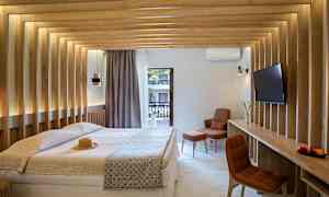 Et moderne hotellrom med en dobbeltseng, trepaneler på veggene og utsikt mot en balkong. Rommet har en TV og en komfortabel sitteplass. (AI-generert tekst)