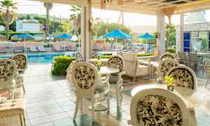 Bilde av en uteservering med bord og stoler, og et basseng med solsenger og parasoller i bakgrunnen. (AI-generert tekst)