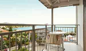 Balkong med bord og stoler, med havutsikt. (AI-generert tekst)