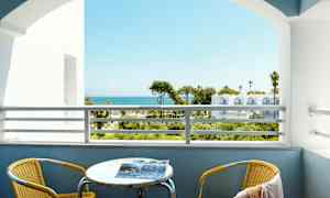 Utsikt fra en balkong med havet i bakgrunnen. En gul stol og et bord er på balkongen. (AI-generert tekst)