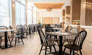 En lys og luftig kafé med svarte stoler og bord. (AI-generert tekst)