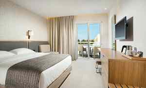 Moderne hotellrom med dobbeltseng, sitteområde og møblert balkong. (AI-generert tekst)