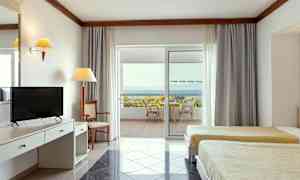 Interiør av et hotellrom med to senger, skrivebord og en uteplass med utsikt over havet. (AI-generert tekst)