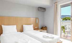 Et hotellrom med to enkeltsenger, en kurvveske og en balkong med utsikt. (AI-generert tekst)