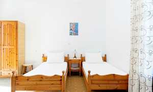 To enkeltsenger med trerammer i et lyst rom med hvite vegger, et lite nattbord med lampe mellom dem. (AI-generert tekst)