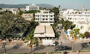 Luftfoto av en bygate med bygninger, en restaurant og kjøretøyer. (AI-generert tekst)