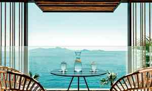 En utendørsplass med et bord hvor en karaffel og tre glass med vann står, med utsikt over et stille hav og øyer i det fjerne. (AI-generert tekst)