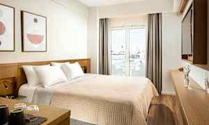 Hotellrom med en dobbeltseng, dekor på veggen, og en glassdør som fører ut til en balkong. (AI-generert tekst)