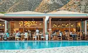 En restaurant ved et basseng med fjell i bakgrunnen. (AI-generert tekst)