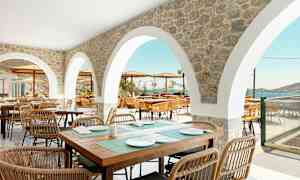 Utendørs servering med steinbuer og sitteplasser med utsikt over havet. (AI-generert tekst)