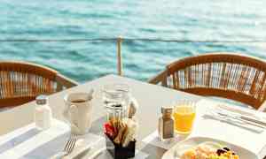 Frokost servert ved bord med utsikt over vannet. (AI-generert tekst)