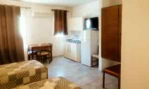 Et rom med to senger, et bord med stoler, et skap og en kjøkkenkrok. (AI-generert tekst)