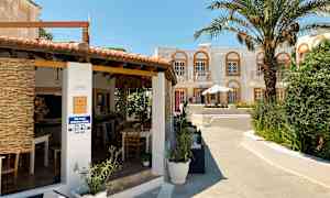 En bygning med terrasse, palmer og en åpen bar. (AI-generert tekst)