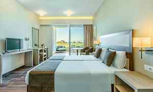 Bilde av et hotellrom med to enkeltsenger, moderne innredning og store vinduer som vender mot en terrasse. (AI-generert tekst)