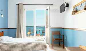 Hotellrom med to senger, utsikt mot en balkong og havet. (AI-generert tekst)