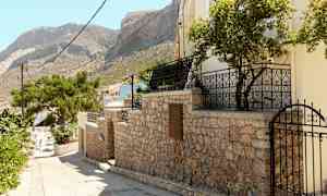 Steinmur med port og trær, fjell i bakgrunnen. (AI-generert tekst)