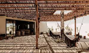 En overbygd uteplass med hengekøyer og skygge fra tretak. (AI-generert tekst)