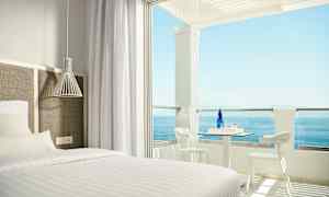 Hotellrom med seng og uteplass med havutsikt. (AI-generert tekst)