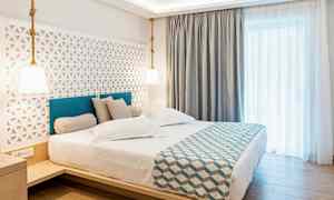 Hotellrom med en dobbeltseng, moderne innredning og lyse gardiner. (AI-generert tekst)