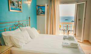 Dobbeltrom med havutsikt gjennom åpne dører til en balkong. (AI-generert tekst)