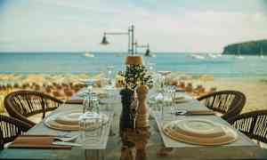Et dekket bord på en restaurant ved stranden med havet i bakgrunnen. (AI-generert tekst)