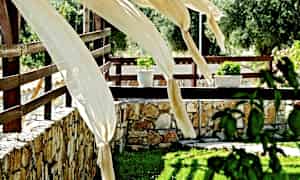 Dekorative tøystykker vaier i vinden på en terrasse med steinmur og blomster. (AI-generert tekst)