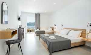 Moderne hotellrom med lyse vegger, dobbeltseng og enkeltseng samt havutsikt. (AI-generert tekst)