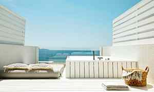 En hvit terrasse med et boblebad, puter og utsikt over havet. (AI-generert tekst)