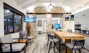 Et interiørbilde av et kontor med sittegruppe, skrivebord og dekorativ steinvegg. (AI-generert tekst)