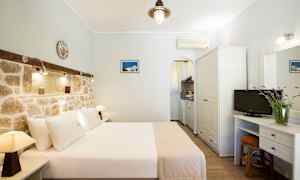 Hotellrom med dobbeltseng, murvegg og liten kjøkkenkrok. (AI-generert tekst)