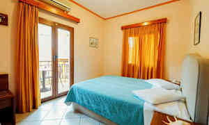 Et hotellrom med en dobbeltseng, gardiner og en balkongdør. (AI-generert tekst)