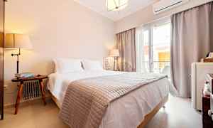 Et hotellrom med en dobbeltseng, nattbord og vindu som slipper inn naturlig lys. (AI-generert tekst)