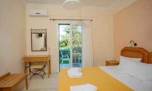 Et hotellrom med en oppredd seng, et skrivebord og en stol, samt en glassdør som fører til en balkong. (AI-generert tekst)