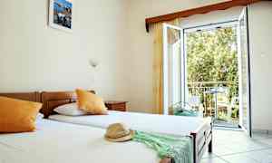 Et hotellrom med enkeltsenger, åpent vindu og utsikt mot balkong. (AI-generert tekst)