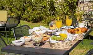 Hagebord med frokost som inneholder frukt, bakverk og drikke. (AI-generert tekst)