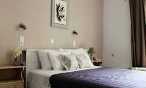 Et soverom med en seng, puter og et mørkelilla sengeteppe. (AI-generert tekst)