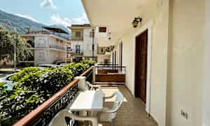 Balkong med bord og stoler med utsikt mot et boligområde med hus. (AI-generert tekst)