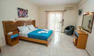 Et hotellrom med en dobbeltseng, maleri over sengen, og glassdører som fører til en balkong. (AI-generert tekst)