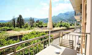 En balkong med utsikt over en grønn dal og fjell i bakgrunnen. (AI-generert tekst)