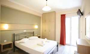 Et lyst hotellrom med en seng, skap og en balkongdør. (AI-generert tekst)