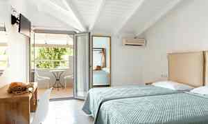 To enkeltsenger i et hotellrom med åpning mot en møblert balkong. (AI-generert tekst)