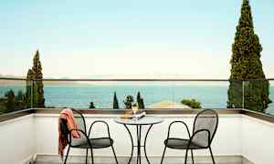 To stoler og et bord på en terrasse med utsikt mot havet. (AI-generert tekst)