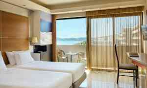 Rom med to enkeltsenger, en balkong med utsikt over havet og sittemøbler. (AI-generert tekst)