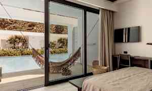 Hotellrom med utsikt mot terrasse med hengekøye og basseng. (AI-generert tekst)