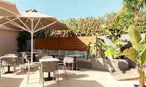 Utendørs sitteområde med bord, stoler og planter. (AI-generert tekst)